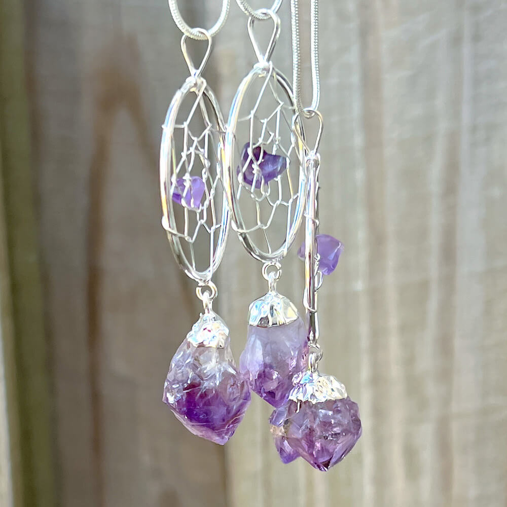 Gorgeous silver plated Amethyst Dreamcatcher Silver Necklace adorned with an Amethyst crystal bead and a raw Amethyst crystal hanging from the bottom. Shop at Magic Crystals for Amethyst Jewelry, Healing Crystals, and Stones. Perfect gift for someone or to wear every day. Boho Jewelry, February Birthstone.