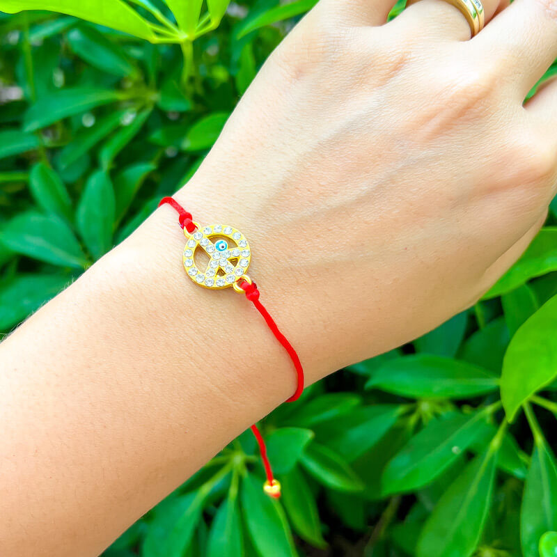 Golden-Piece-Sign-Red-String-Bracelet. Shop at Magic Crystals for Protection. The Red String Bracelet has been worn throughout history in many cultures as a symbol of protection, faith, and good luck and acts as a shield from negativity and actually has many positive effects. In quite a few cultures a red string bracelet is believed to have magical powers.