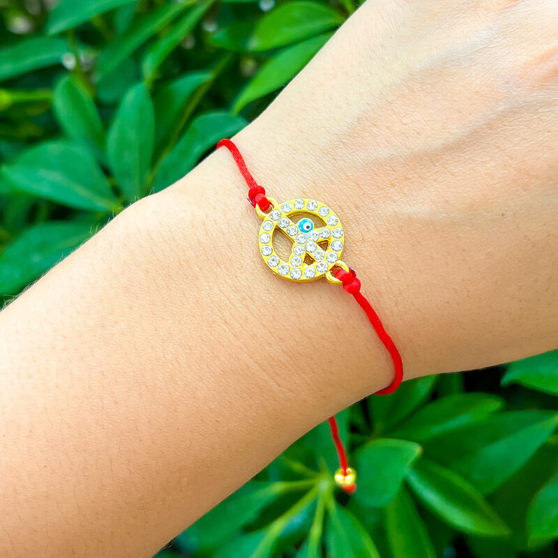 Golden-Piece-Sign-Red-String-Bracelet. Shop at Magic Crystals for Protection. The Red String Bracelet has been worn throughout history in many cultures as a symbol of protection, faith, and good luck and acts as a shield from negativity and actually has many positive effects. In quite a few cultures a red string bracelet is believed to have magical powers.