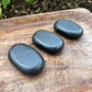 Large natural black Shungite palm stone with smooth polished oval surface on a 
hand from MagicCrystals.com